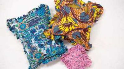 three brightly colored pillows of different sizes, each with a ruffled edge