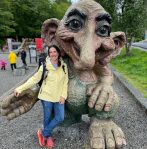 Woman standing with troll statue.
